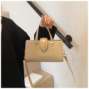 Vue détaillée du sac à main beige en cuir avec boucle argentée et bandoulière réglable