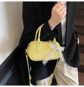 Detail of yellow Boston bag showing the lace bow, pearl chain and lychee texture