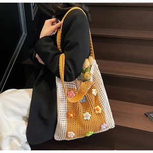 Détail d'un sac cabas floral tissé à la main en jaune et blanc, posé sur un escalier