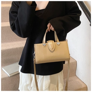 Détail d'un sac à main carré beige élégant avec boucle argentée et bandoulière réglable