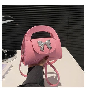 Pink lychee texture mini handbag with silver metal bow and integrated handle detail