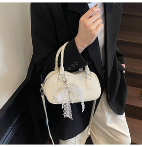 Detail of cream Boston bag with elegant pearl lace bow charm on the textured leather handle