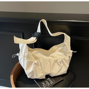 Détail d'un cabas en nylon beige avec poches réglables à cordon et boucles noires