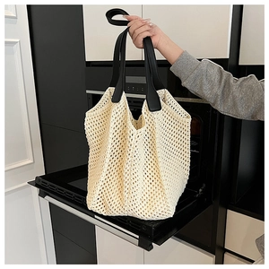 Close-up of cream hollow woven tote bag with contrasting black faux leather handles