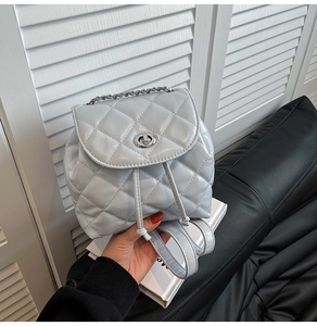 Detail showing the light blue quilted faux leather texture and silver twist lock on mini backpack