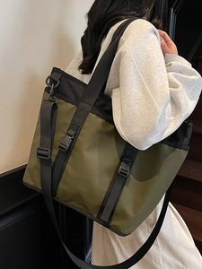 Large capacity dark green oxford tote bag shown on model with adjustable strap