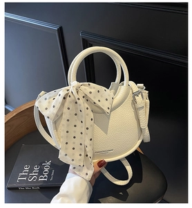 Détail du sac seau blanc en cuir grainé avec foulard à pois et logo embossé sur le dessous