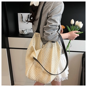 Detailed close-up of cream woven tote bag with contrast black leather strap in casual style
