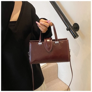 Détail d'un sac à main en cuir ciré bordeaux avec des boucles métalliques argentées