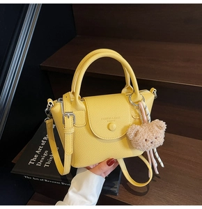 Détail du sac à main en cuir jaune grainé avec boucle ronde et charm d'ours en peluche