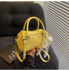 Detail of yellow lychee grain leather mini bag with lace pearl bow charm and top handles