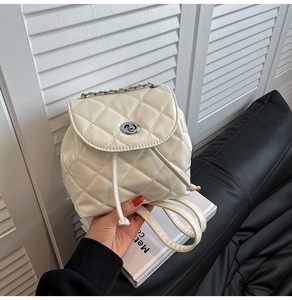 Close-up of cream quilted leather mini backpack with silver metal turn-lock and chain handle