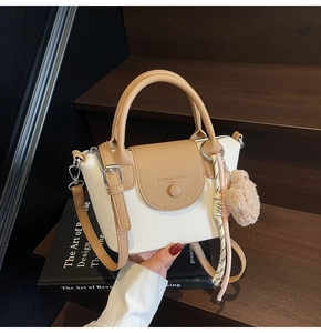 Détail du mini sac à main texture lychee avec pompon en peluche et poignée foulard