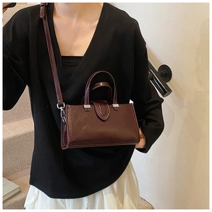Détail du cuir ciré bordeaux foncé sur un sac à main rectangulaire à bandoulière