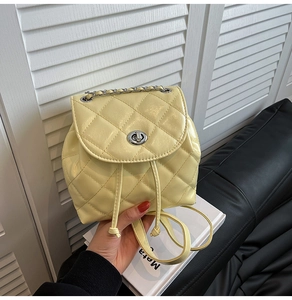 Detail of light yellow quilted mini backpack with silver metal twist lock and chain
