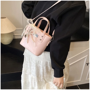 Close-up of pink PU bucket bag with lace trim and pearl bow charm on a model