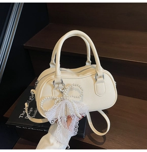 Close-up of cream Boston bag with lychee texture and pearl bow lace decoration