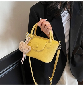 Détail d'un sac à main jaune texture lychee avec breloque ours et bandoulière