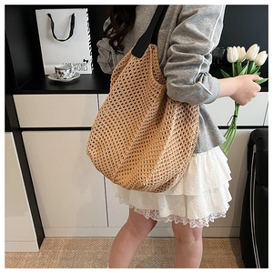 Close-up of hollow woven tote bag featuring black shoulder straps and a natural brown texture