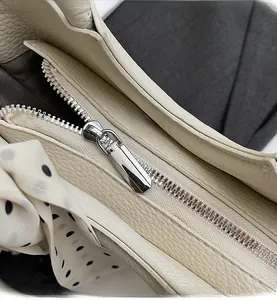 Vue rapprochée de la fermeture éclair en métal argenté et cuir grainé du sac seau blanc