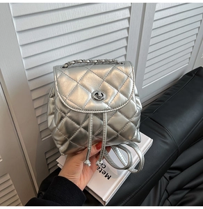 Detailed view of silver quilted backpack with metal chain handle and twist lock closure