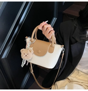 Détail du sac à main motif litchi avec poignée marron et breloque ours en peluche