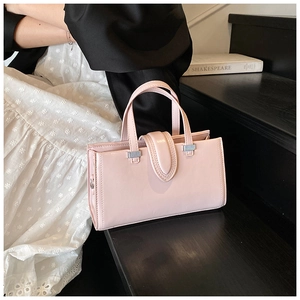 Détail d'un sac à main rose en cuir ciré avec boucles en métal argenté sur un support noir