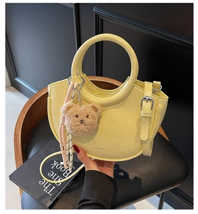 Detail of light yellow bucket bag with crinkled texture and cute bear charm accessory