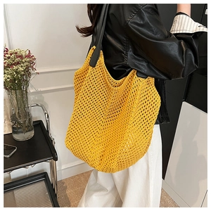 Detail of a bright yellow crochet knit tote bag with black leather shoulder straps