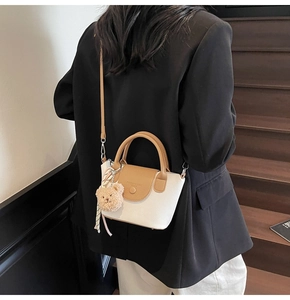 Détail du sac blanc à motif litchi avec poignée marron et breloque petit ours