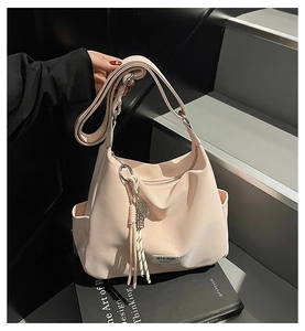 Detail of light pink waterproof tote bag featuring a side pocket and decorative fringe charm