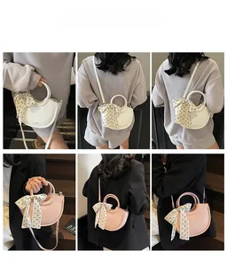 Détail du sac bandoulière demi-lune en cuir avec poignée anneau et détail foulard à pois