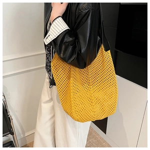 Close-up of bright yellow crochet mesh tote bag featuring a durable black leather shoulder strap
