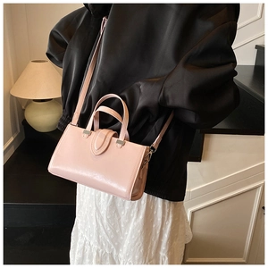 Détail d'un sac à main en cuir verni rose clair avec bandoulière porté par un mannequin