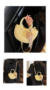 Detail of light yellow crescent bucket bag with brown teddy bear charm and fringe