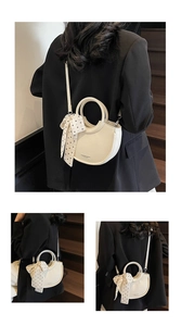 Détail d'un sac seau en cuir beige crème avec un foulard à pois chic et une poignée