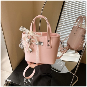 Detailed macro of pink PU leather bucket bag with pearl bow and lace ribbon accent