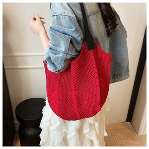 Detailed view of red woven hollow tote bag with black leather shoulder strap on model
