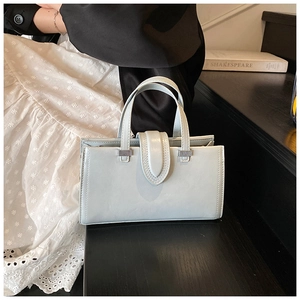 Détail d'un sac à main bleu gris en cuir avec coutures fines et ferrures en argent