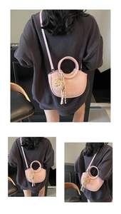 Detailed view of pink PU leather half-moon bag featuring a cute brown plush bear charm