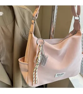 Close-up of pink shoulder bag featuring a woven rope knot and silver abacus pendant