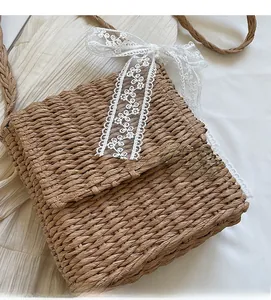 Detail view of woven straw shoulder bag with delicate white lace bow decoration