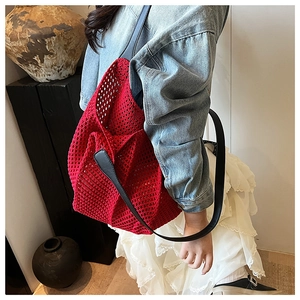 Detail of red woven tote bag with black leather straps styled in an artistic studio