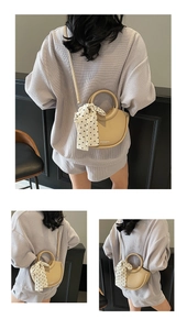 Vue détaillée du sac croissant beige en cuir grainé avec poignée ornée d'un foulard