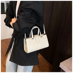 Détail d'un sac à main en cuir crème avec des coutures fines et des ferrures argentées