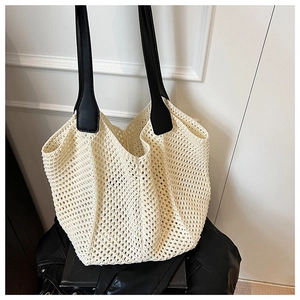 Detail of hollow woven knit tote bag with contrasting black leather wide shoulder handles