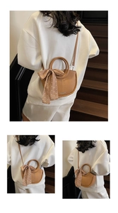 Détail d'un sac seau en cuir marron avec un foulard en soie attaché à la poignée