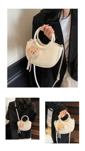 Detail view of cream bucket bag with ring handle and plush bear charm decoration