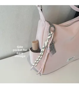 Detailed view of side pocket on pink nylon crescent tote bag with woven cord accessory