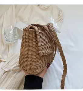 Detail of woven straw shoulder bag with white lace bow and braided crossbody strap